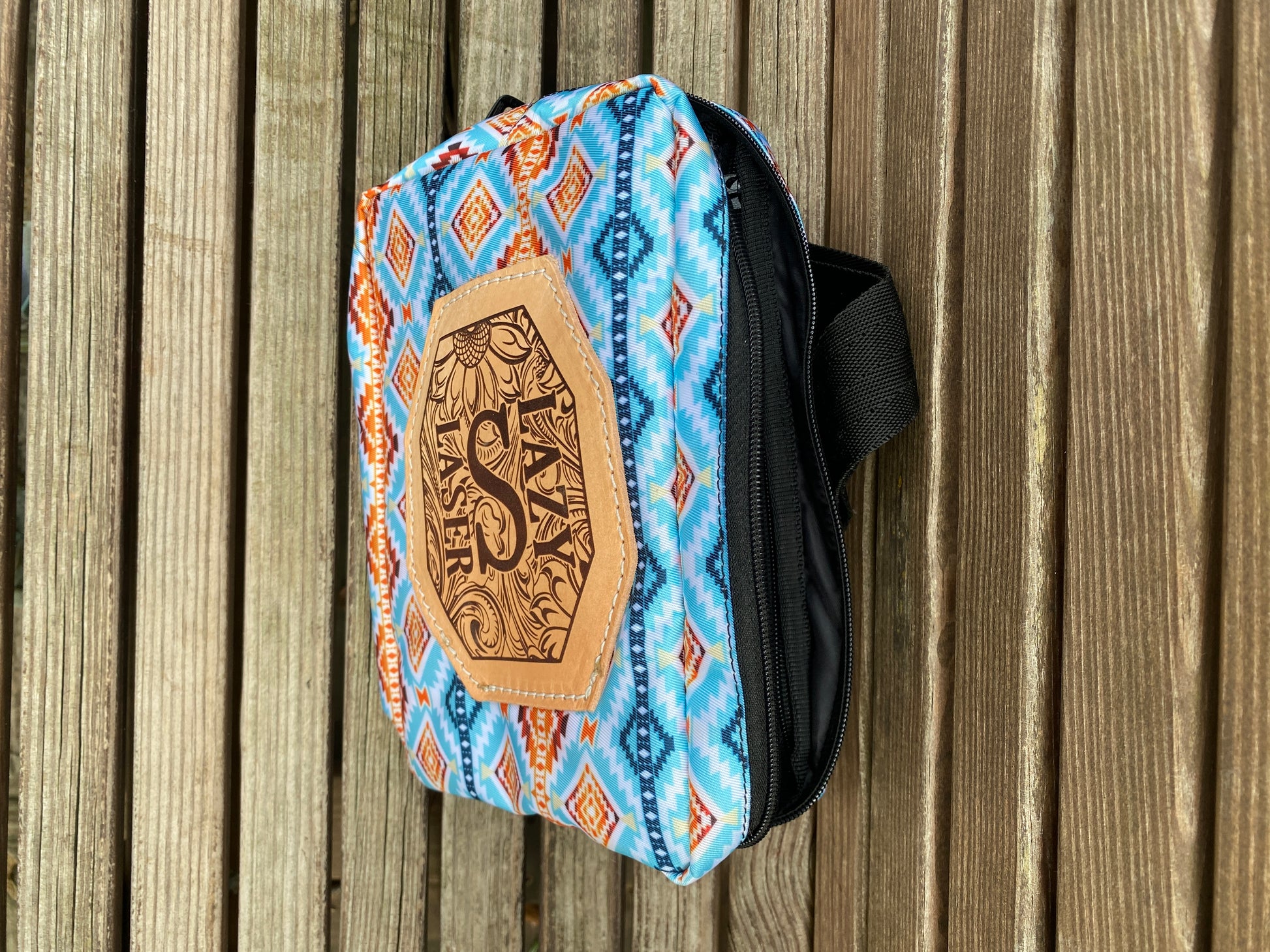 Engraved leather patch on western fanny pack on a wooden surface, top-down view