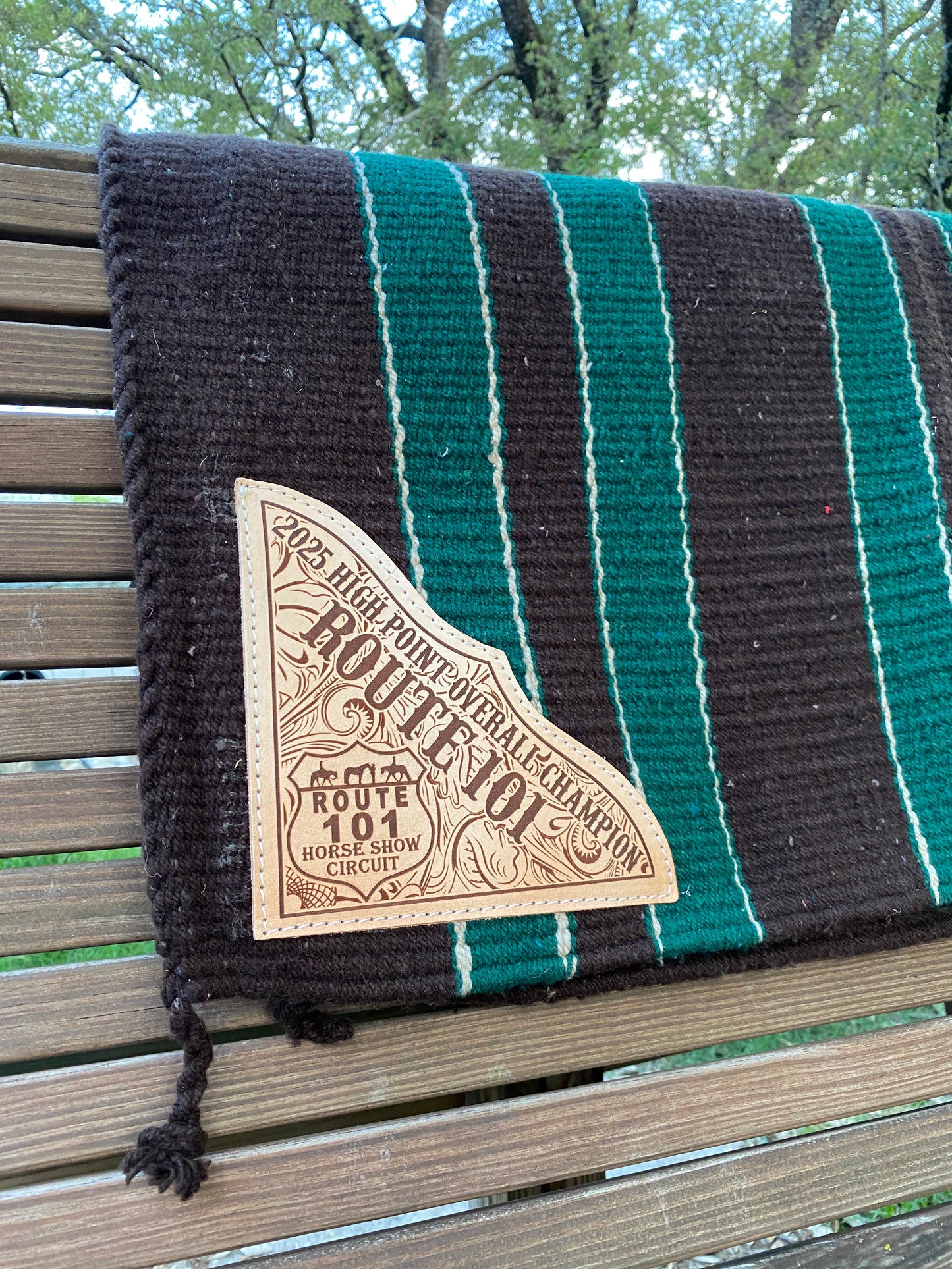 custom engraved western saddle pad with green and brown color band stripe pattern and tassels at the end