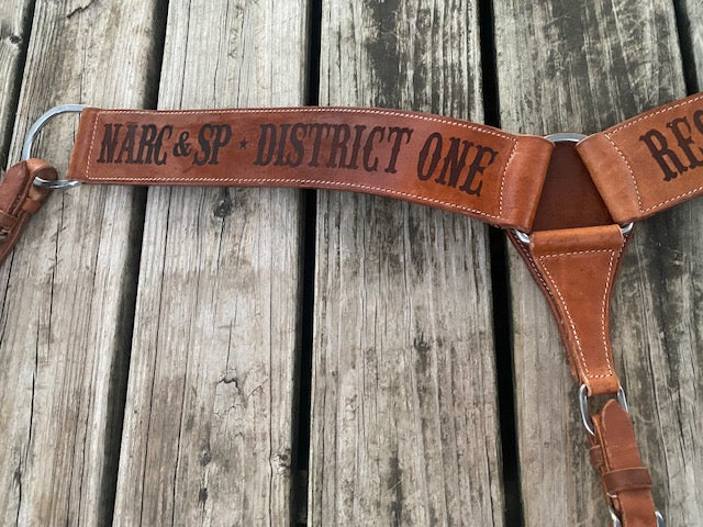 Roper style breast collar strap with lasered text on a wooden background