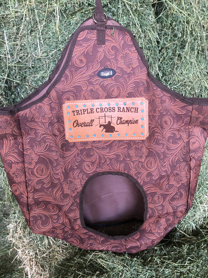 Tough 1 Brown Leather Tooled Hay Bag with a customized leather award patch for a western cowboy church, presented on a background of fresh alfalfa.