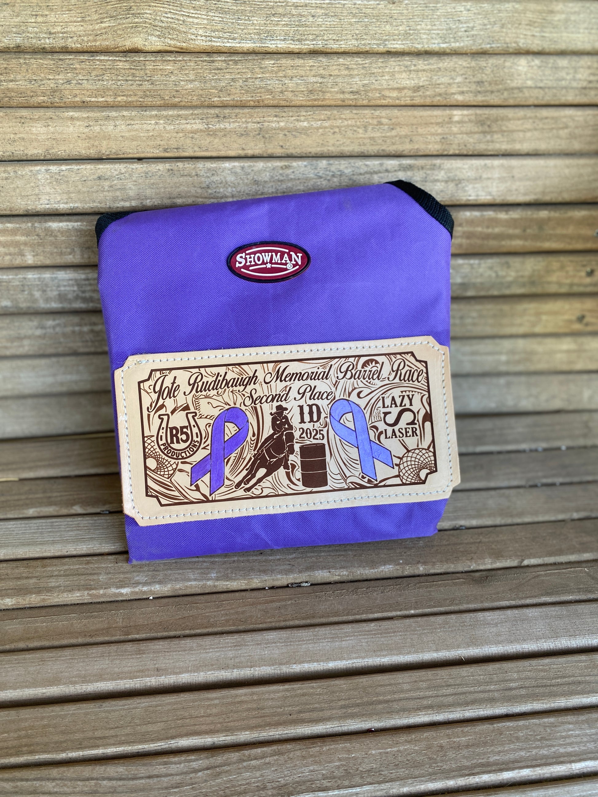 Custom laser engraved award hay bag for rodeos and horse shows folded on a wooden bench