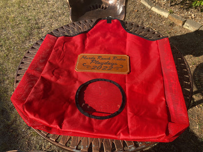 Red hay bag presented on a metal table with a leather patch award for a ranch rodeo playday