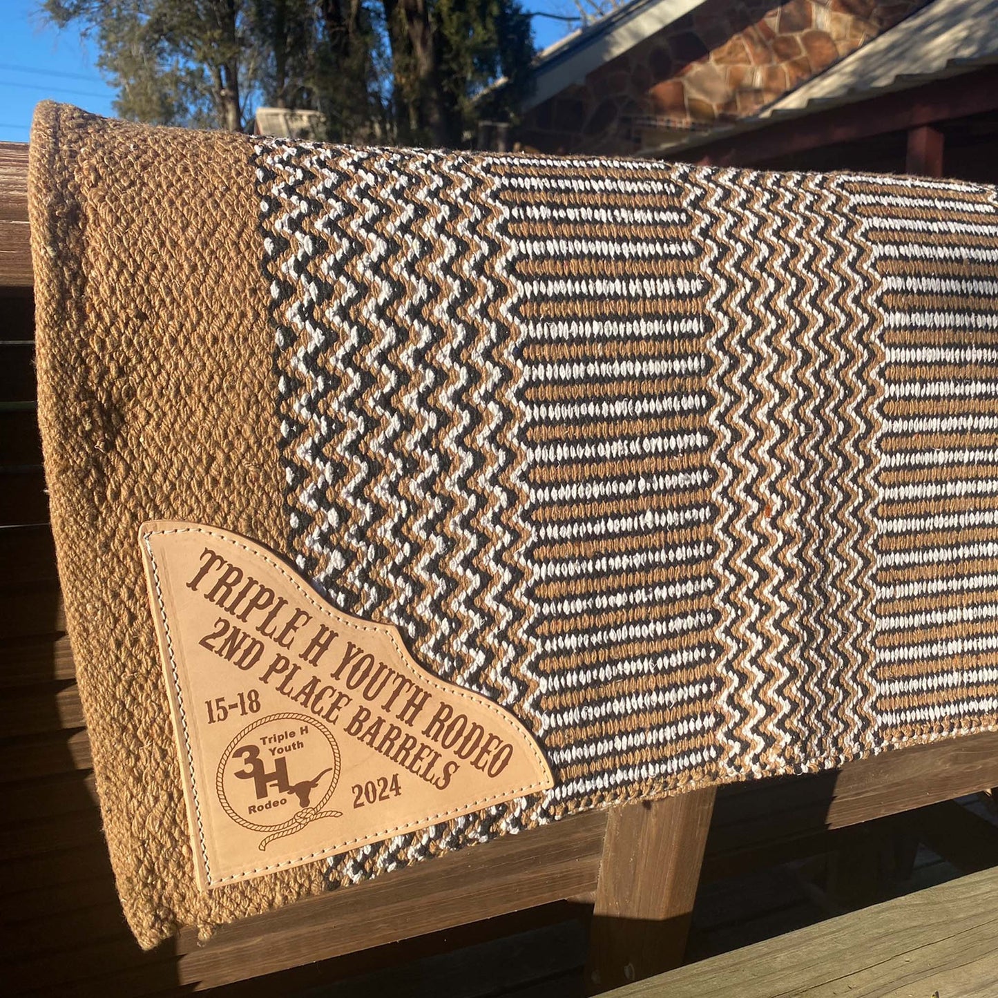tan zigzag saddle blanket double weave displayed outdoors highlighting engraved leather corner