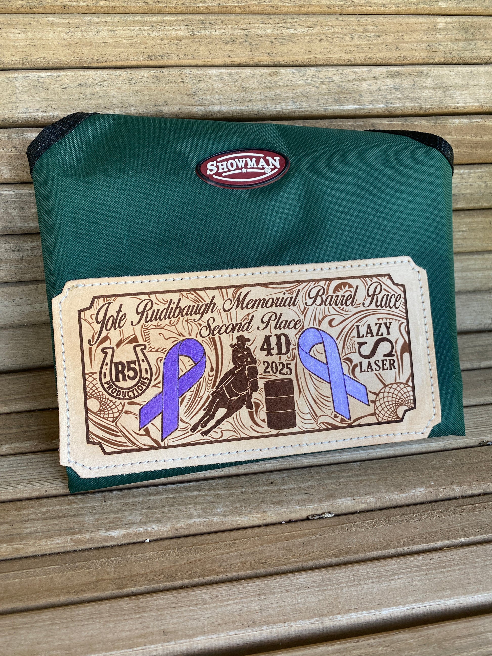 Green hay bag with a laser engraved patch featuring barrel racer art and purple ribbons